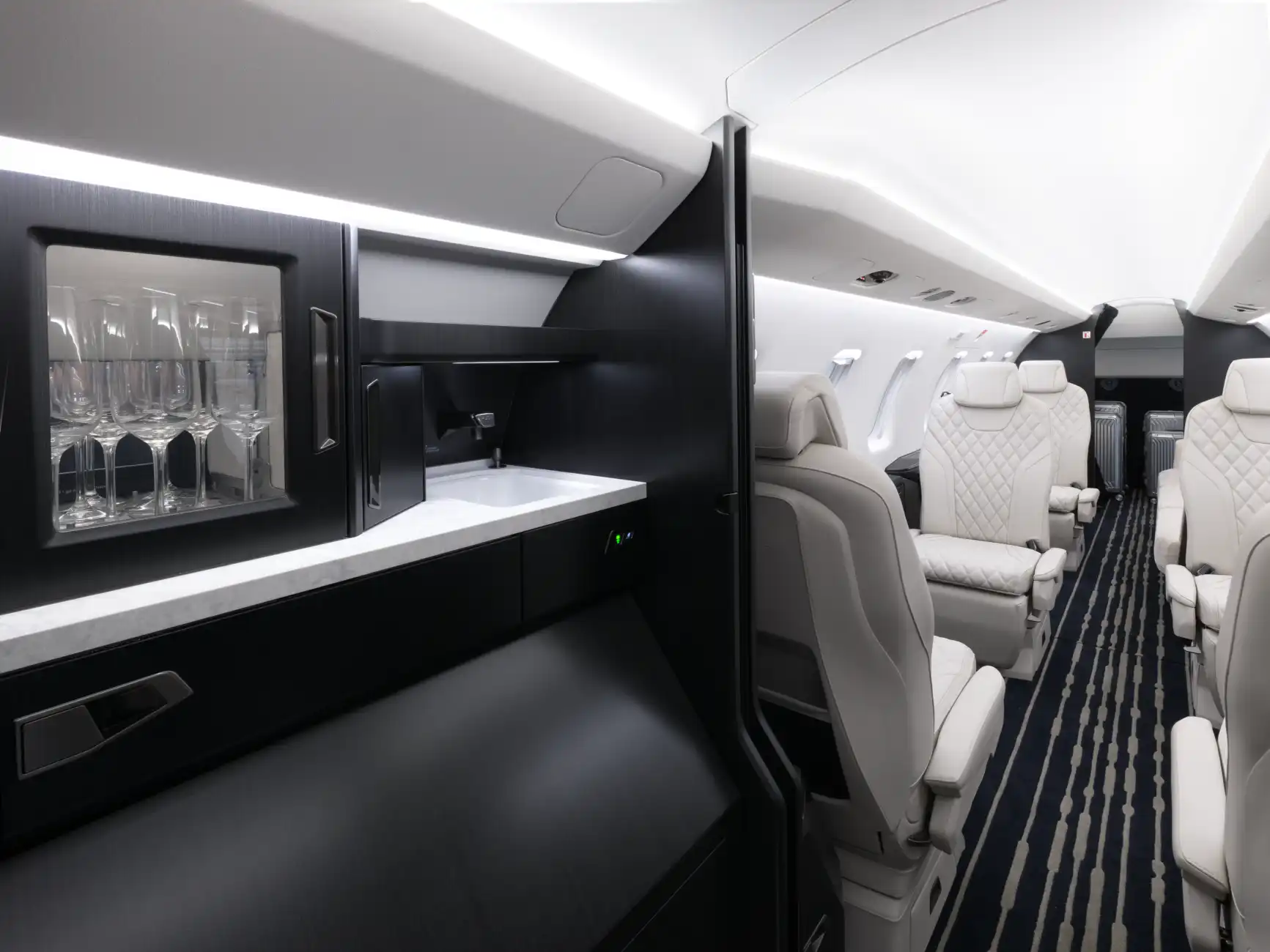 The PC-24 cabin shows the "kitchen" with champagne glasses on a shelf and a sink