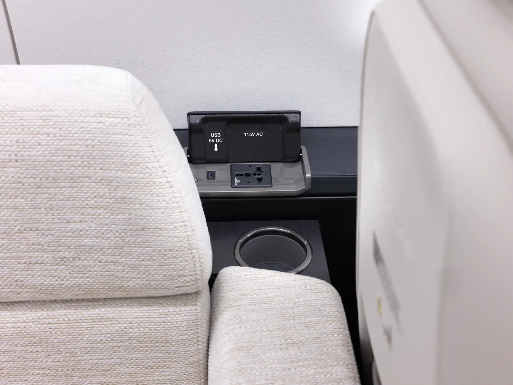 The PC-24 cabin shows a drink holder and an outlet behind the divan