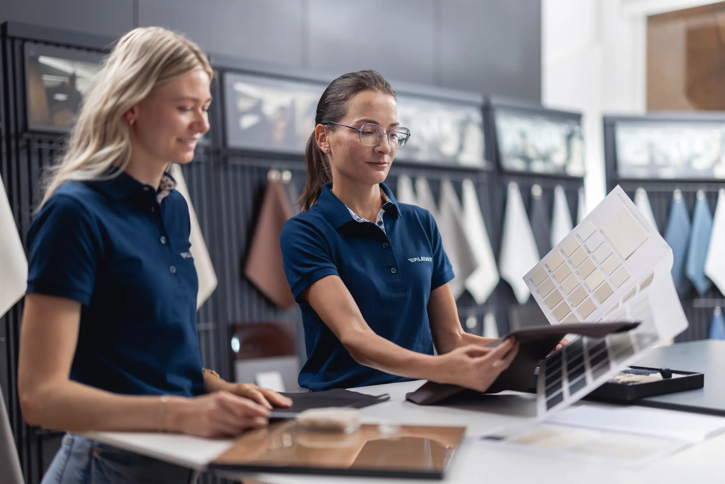 Two female employees in the spec room, looking at fabrics and colors.